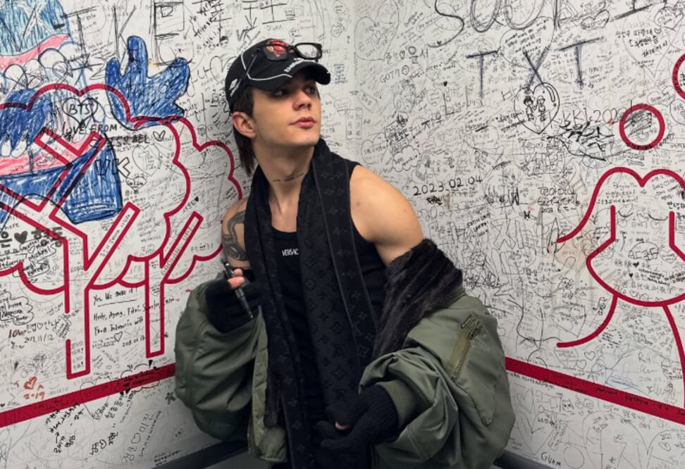 Carlos Alberto con un look de streetwear junto a una pared de grafiti
